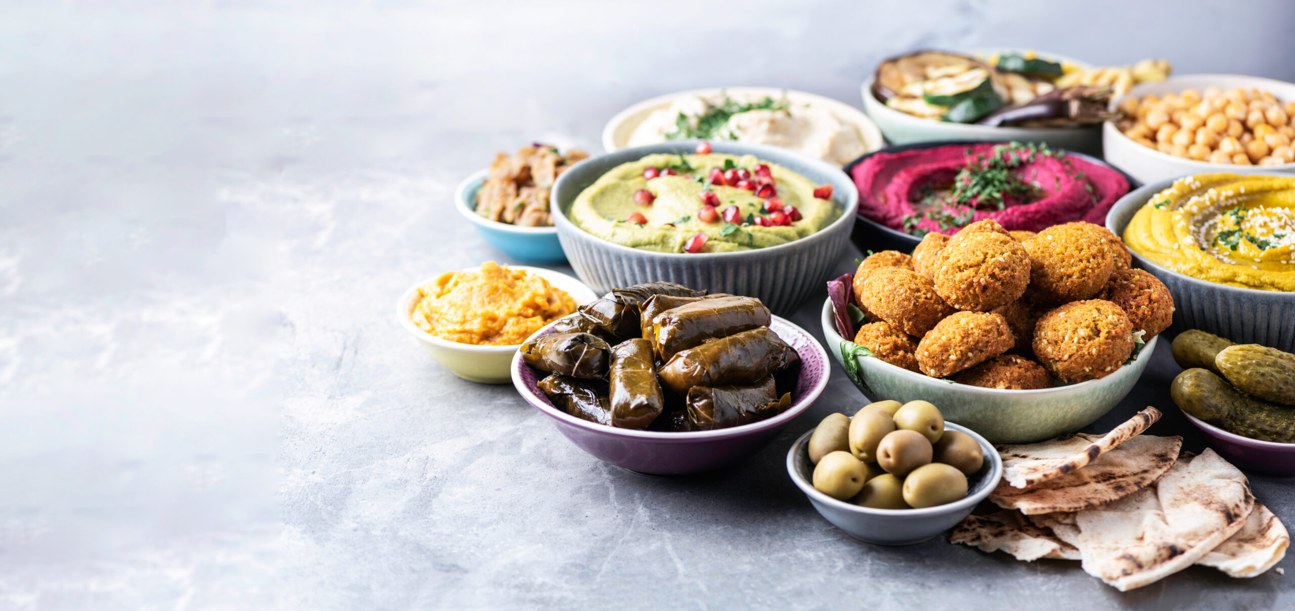 Mediterranean appetizer concept. Arabic traditional cuisine. Middle Eastern meze with pita, olives, hummus, stuffed dolma, falafel balls, pickles, babaganush, vegetables, pomegranate, eggplants